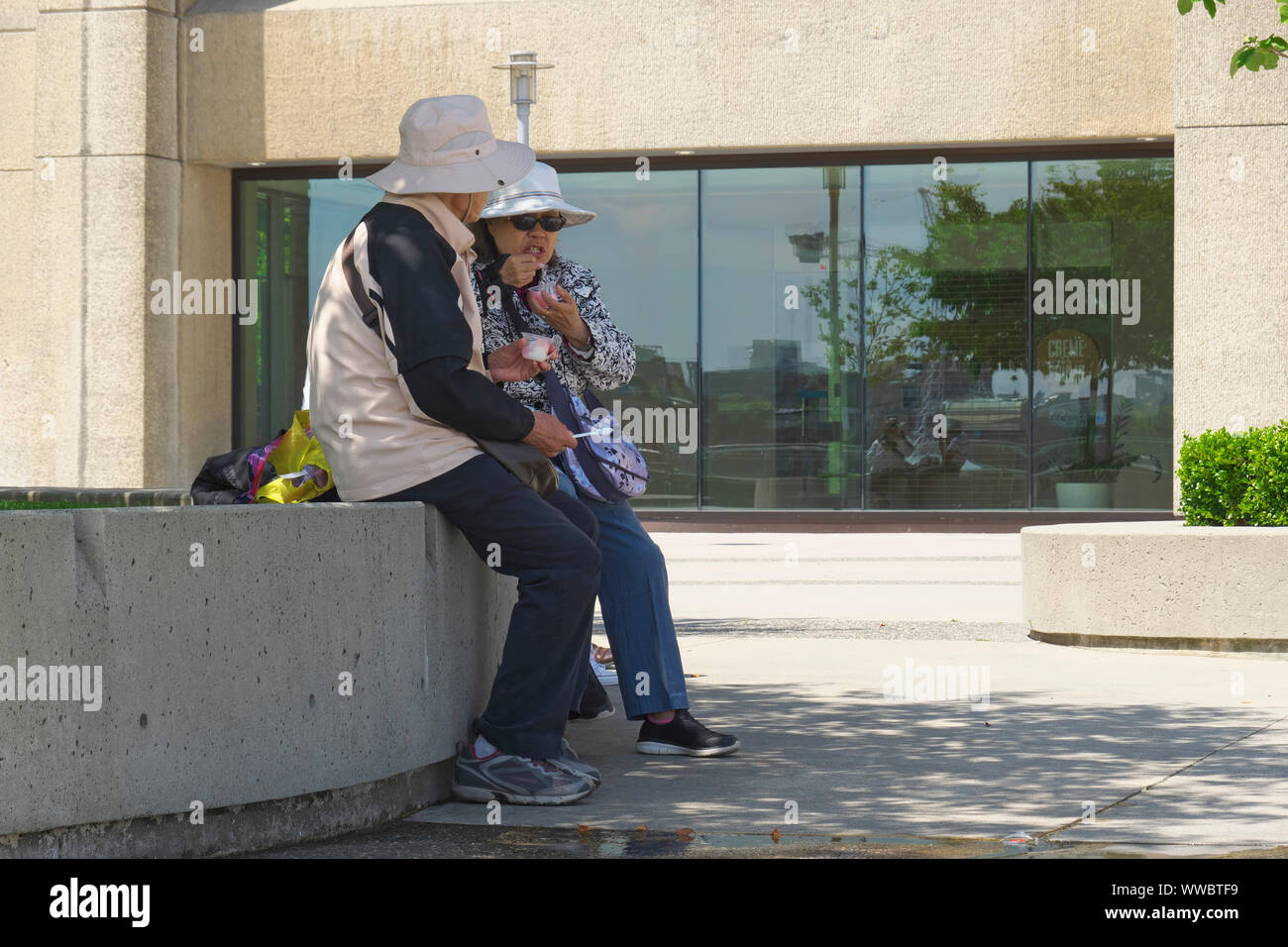 Asian Couple Eating Outside in Granville Square, Vancouver, B. C., Canada. June 15, 2019 Stock Photo