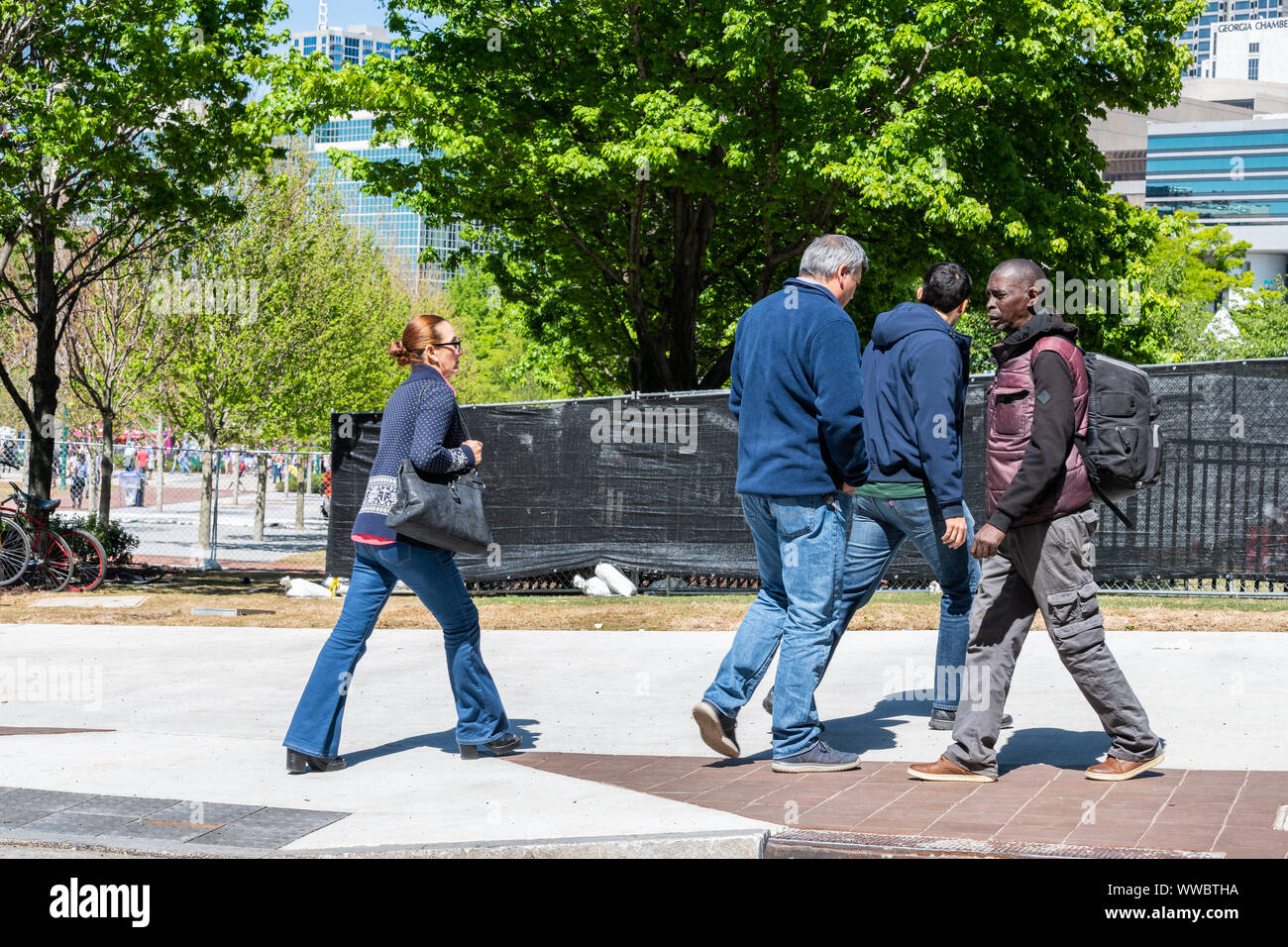 Atlanta, USA - April 20, 2018: People walking on street road sidewalk by Centennial Olympic park with office buildings skyscrapers in background in Ge Stock Photo