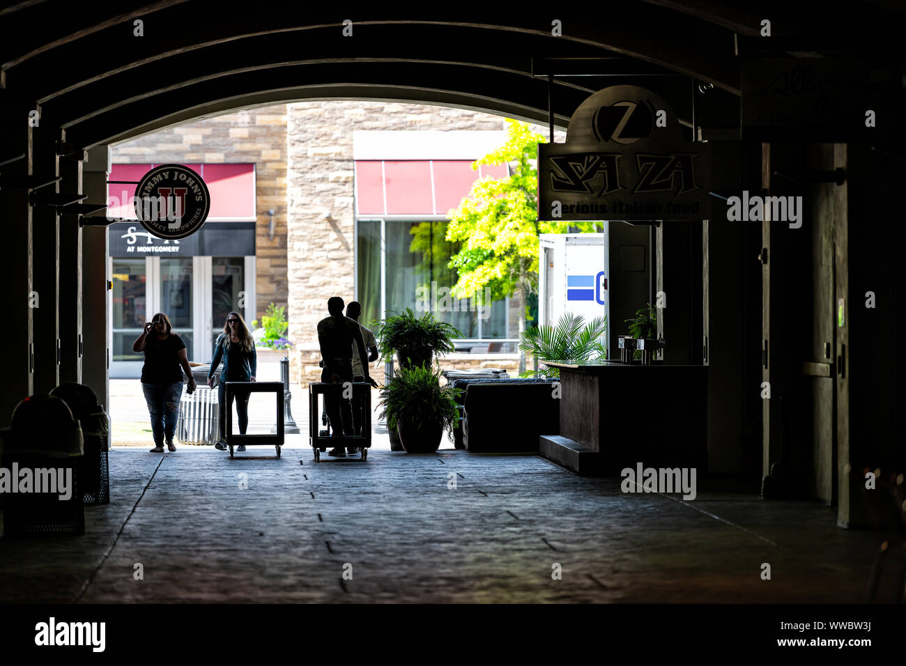 Montgomery, USA - April 21, 2018: The Alley tunnel or passage with people walking by Jimmy John's gourmet sandwich shop, Sa Za Italian restaurant in A Stock Photo