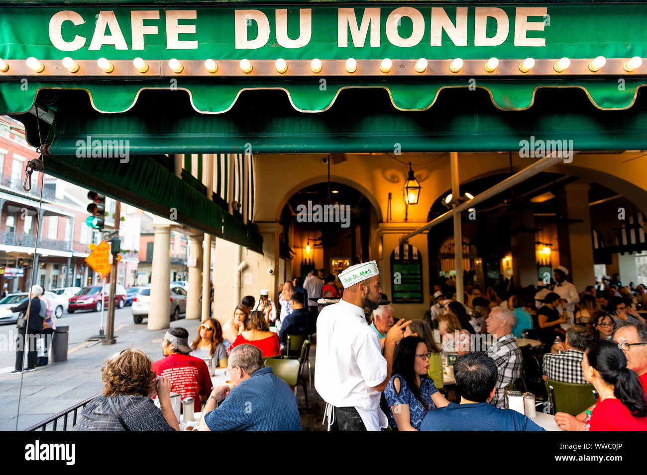 New Orleans, USA - April 22, 2018: People ordering food in Cafe Du Monde restaurant, eating beignet powdered sugar donuts, drinking chicory coffee, wa Stock Photo