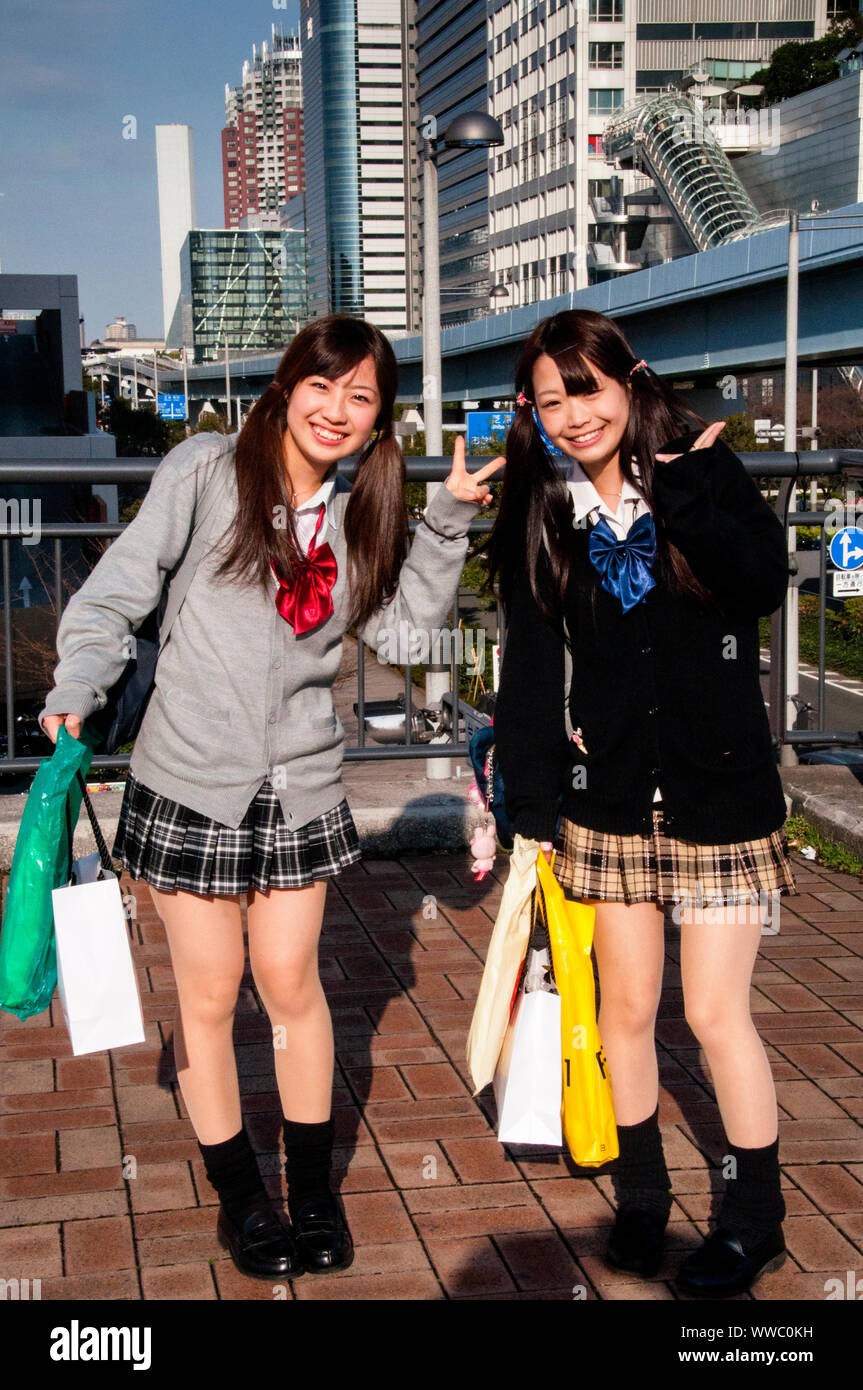 Young Japanese women in Odabia wearing lolita style clothing with a warm smile and peace symbol welcome on a cold afternoon. Stock Photo