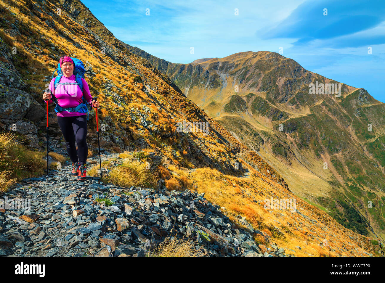 Happy active sporty hiker woman with backpack on alpine hiking trails, Fagaras mountains, hiking and travel concept, Carpathians, Romania, Europe Stock Photo