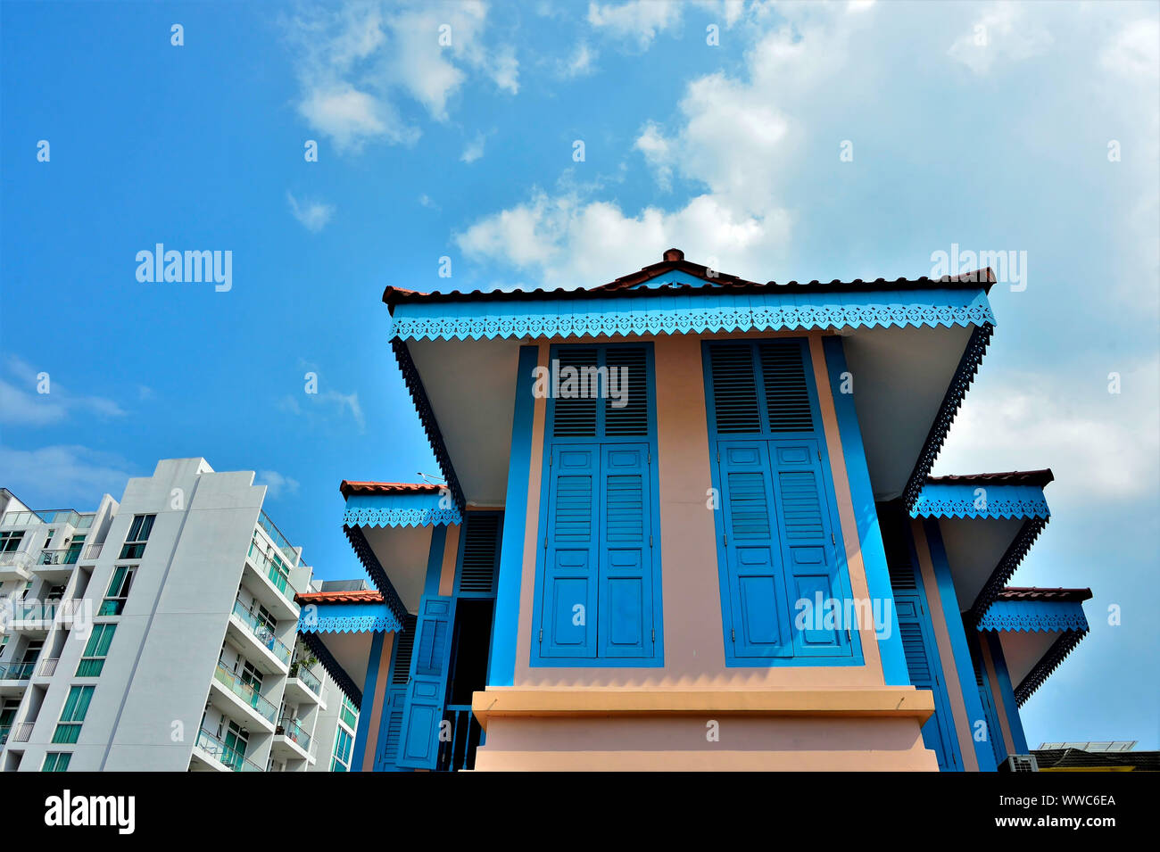 Traditional Malay house with wide gables and blue wooden shutters against sky in historic Geylang, Singapore Stock Photo