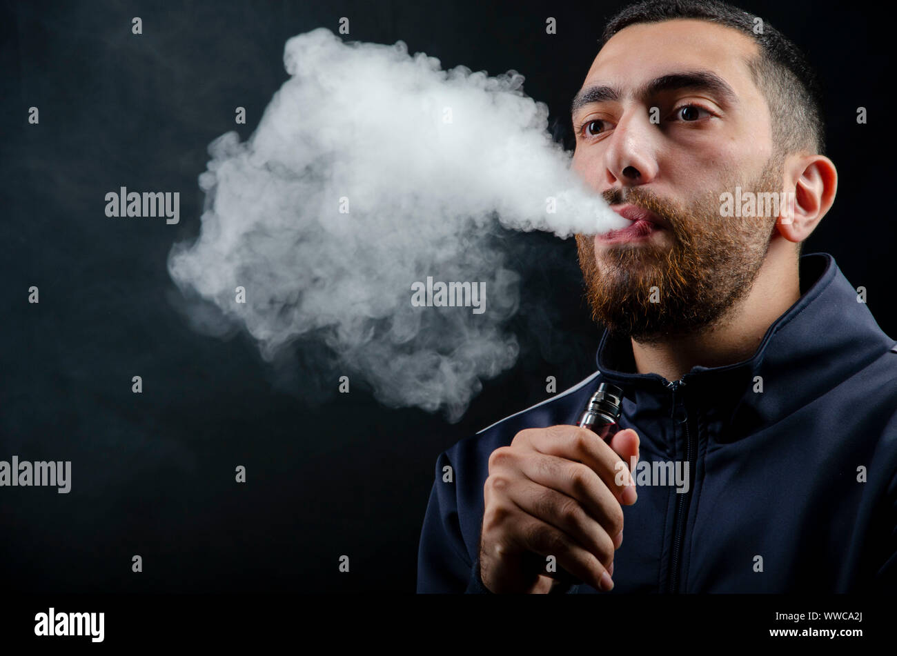 man holding vape e-cigarette or electronic cigarette with white smoke over  a black background Stock Photo - Alamy