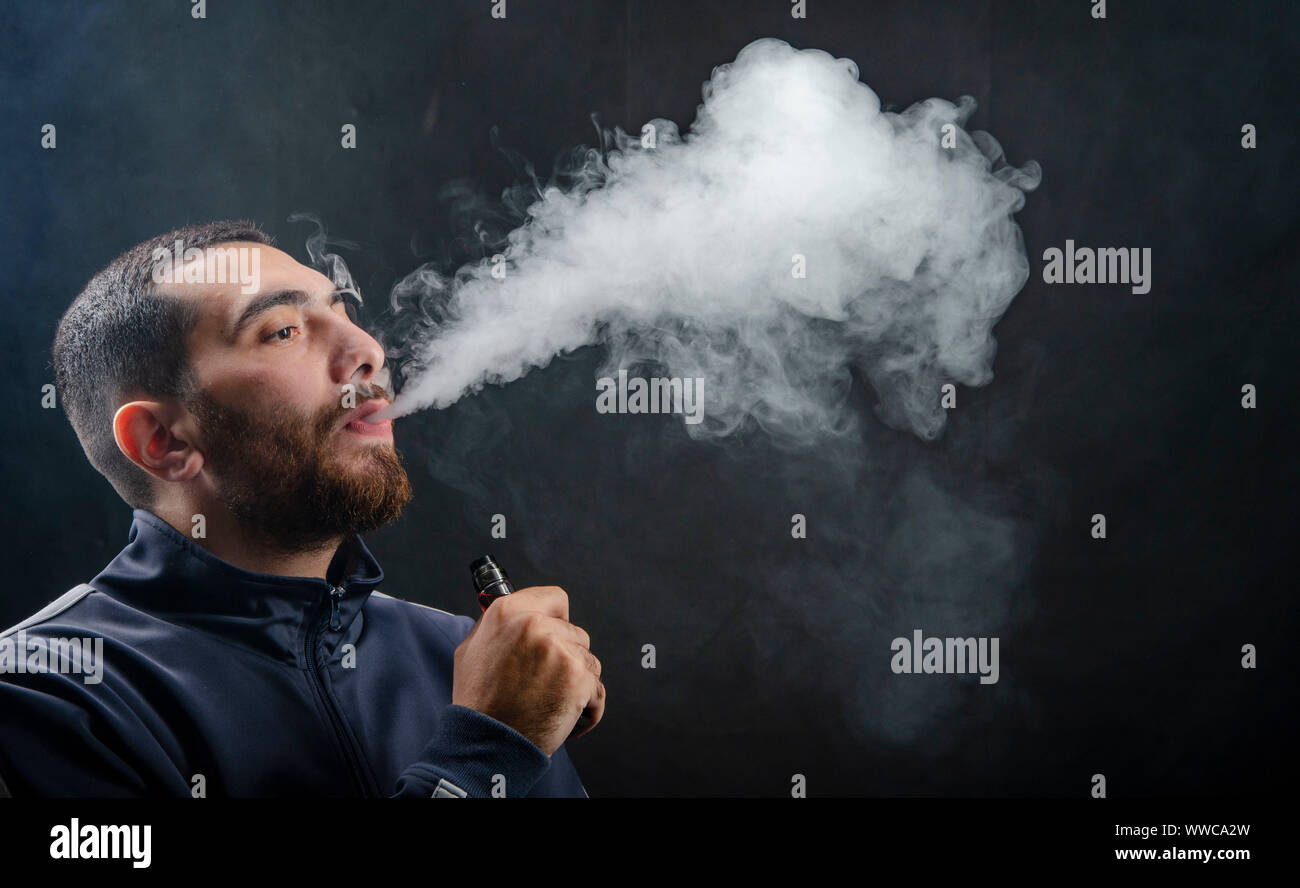 man holding vape e-cigarette or electronic cigarette with white smoke over  a black background Stock Photo - Alamy
