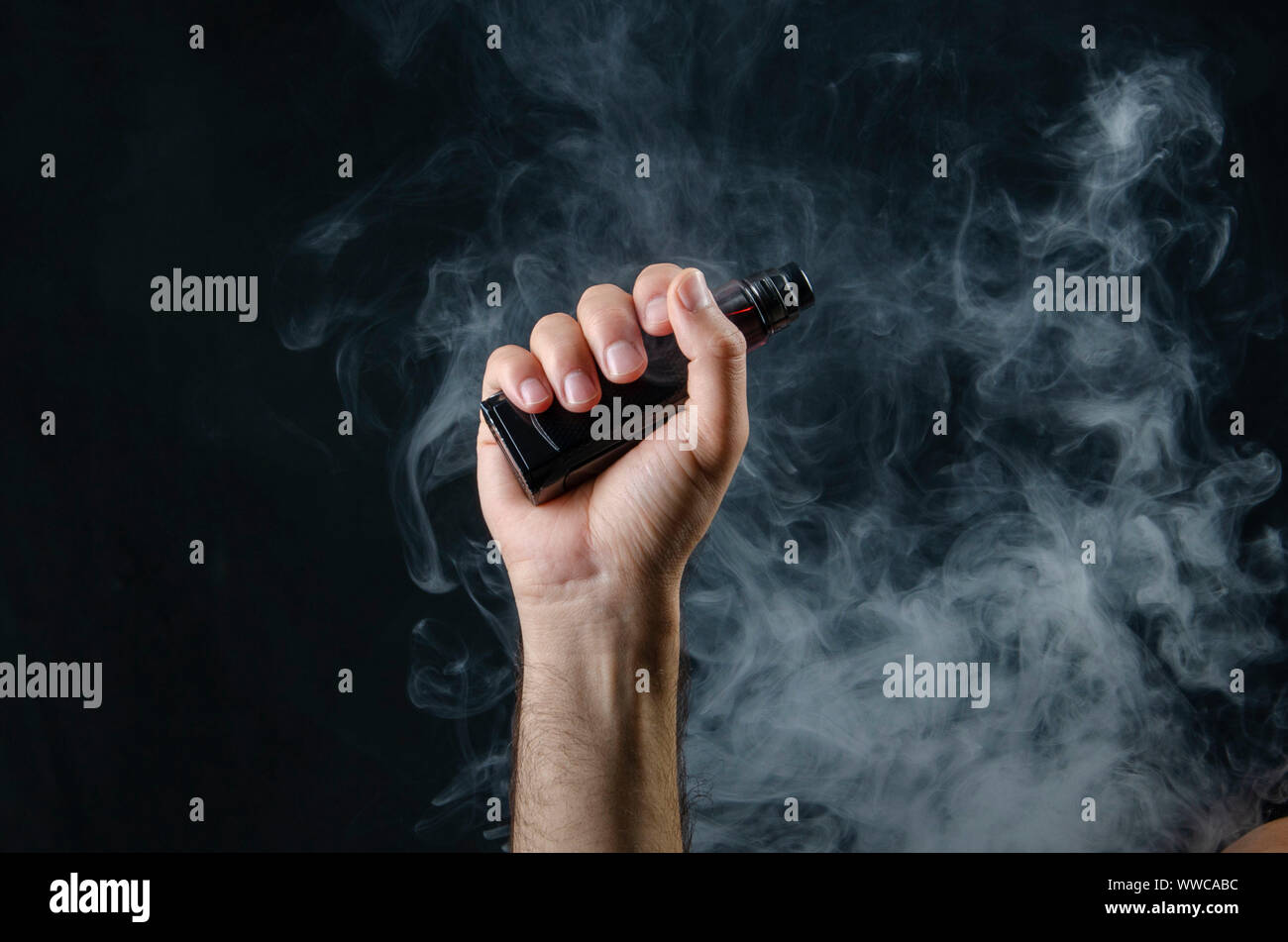 hand holding vape e-cigarette or electronic cigarette with white smoke over  a black background Stock Photo