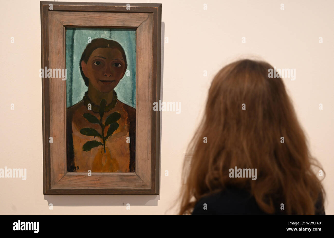Bremen, Germany. 12th Sep, 2019. An employee of the Paula Modersohn-Becker Museum looks at Paula Modersohn-Becker's painting 'Self-Portrait with Camellia Branch', 1906/07. In the special exhibition 'I am me. Paula Modersohn-Becker. Die Selbstbildnisse' will be shown for the first time around 50 of a total of over 60 self-portraits by Paula Modersohn-Becker (1876-1907). The painter is regarded as one of the most important representatives of early Expressionism. The exhibition can be seen from 15.9. to February 2020. Credit: Carmen Jaspersen/dpa/Alamy Live News Stock Photo