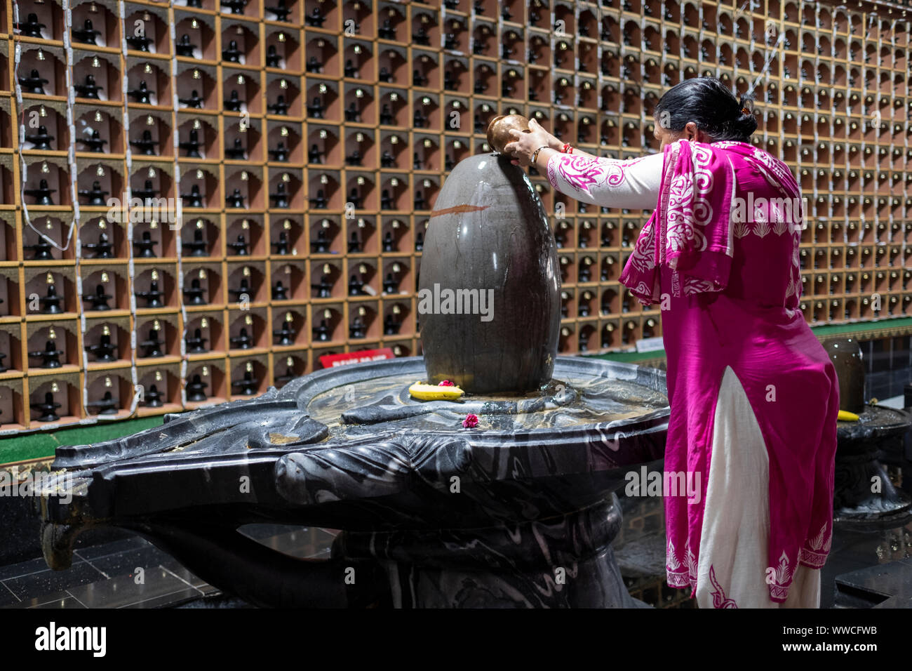 A devout Hindu woman pours water on a Shiva Lingam inside a temple in Woodside, Queens, New York City. Stock Photo