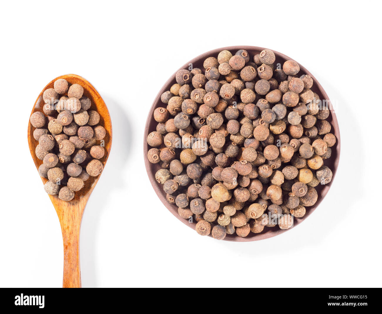 Allspice (Jamaica pepper) in the clay plate and wooden spoon vertically