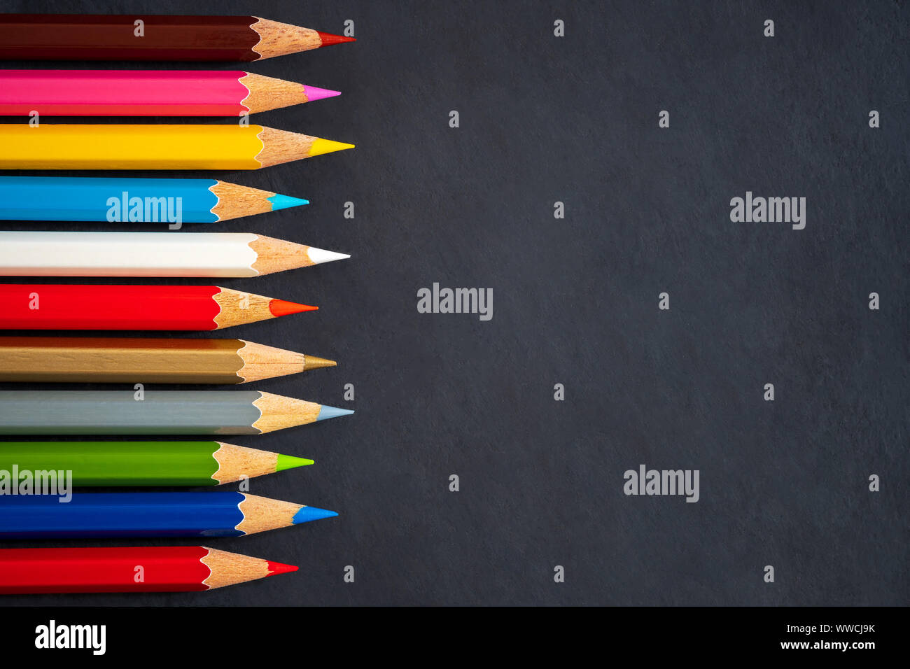 Colored pencils on chalkboard background. Top view and copy space