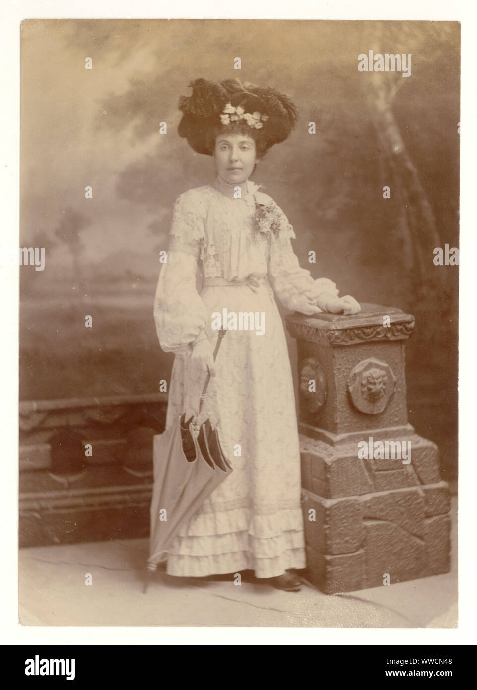 Original, clear, Edwardian Studio portrait photograph of fashionable glamorous Edwardian lady wearing a summer outfit, elaborate hat adorned with many feathers, holding a parasol, circa 1903, U.K. Stock Photo