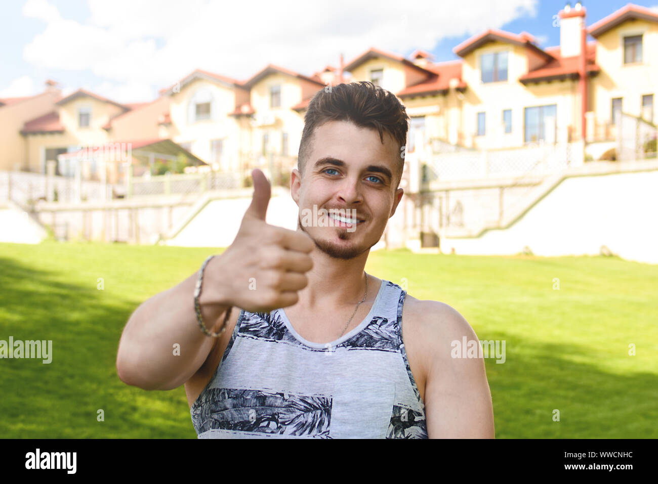 Attractive resting man with thumb up. beautiful cottages in the background Stock Photo