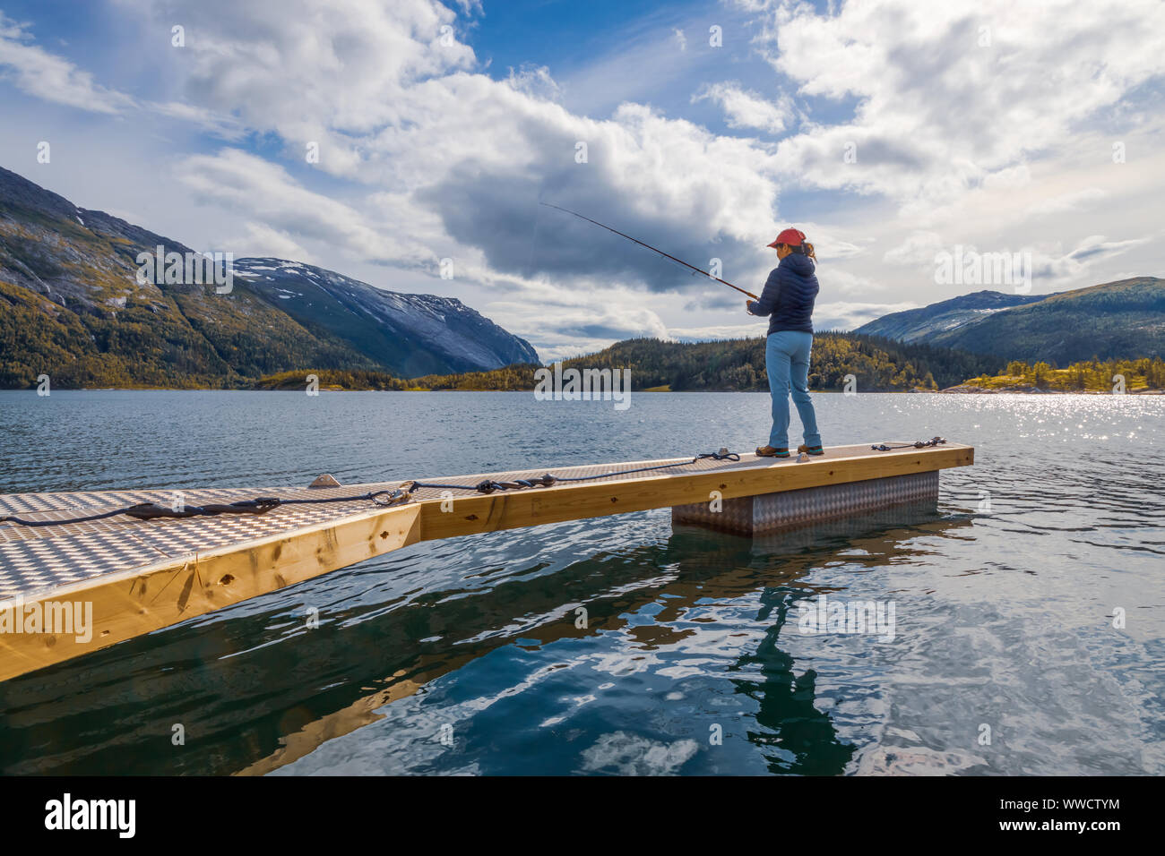 Woman fishing on Fishing rod spinning in Norway. Fishing in Norway is a way to embrace the local lifestyle. Countless lakes and rivers and an extensiv Stock Photo