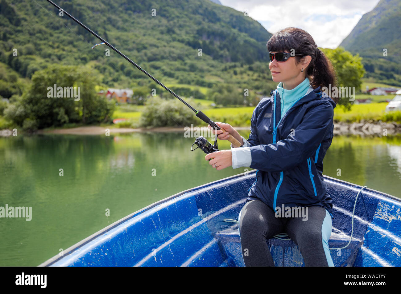 Woman fishing on Fishing rod spinning in Norway. Fishing in Norway is a way to embrace the local lifestyle. Countless lakes and rivers and an extensiv Stock Photo