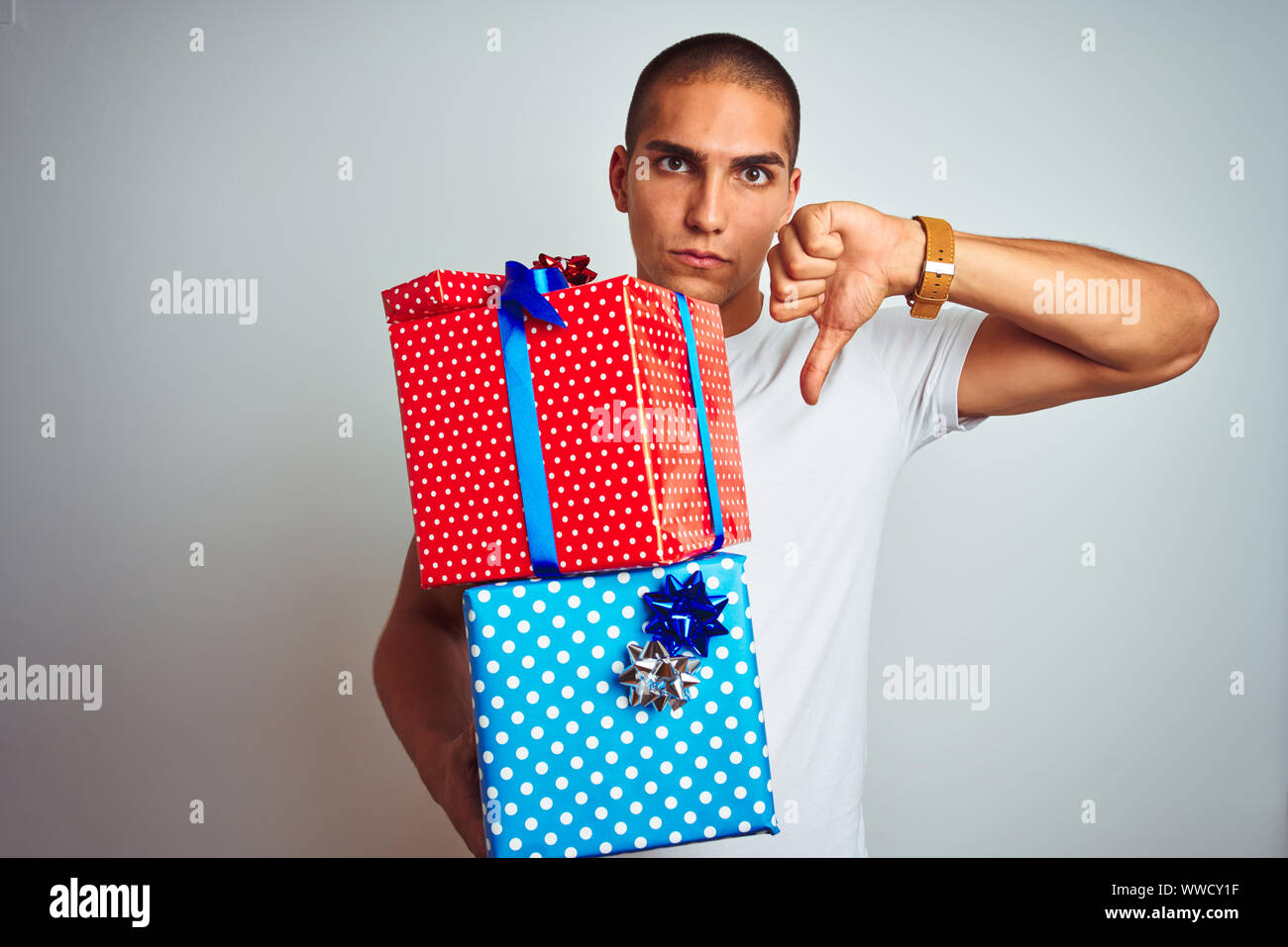 Young handsome man holding birthday gifts over white isolated ...