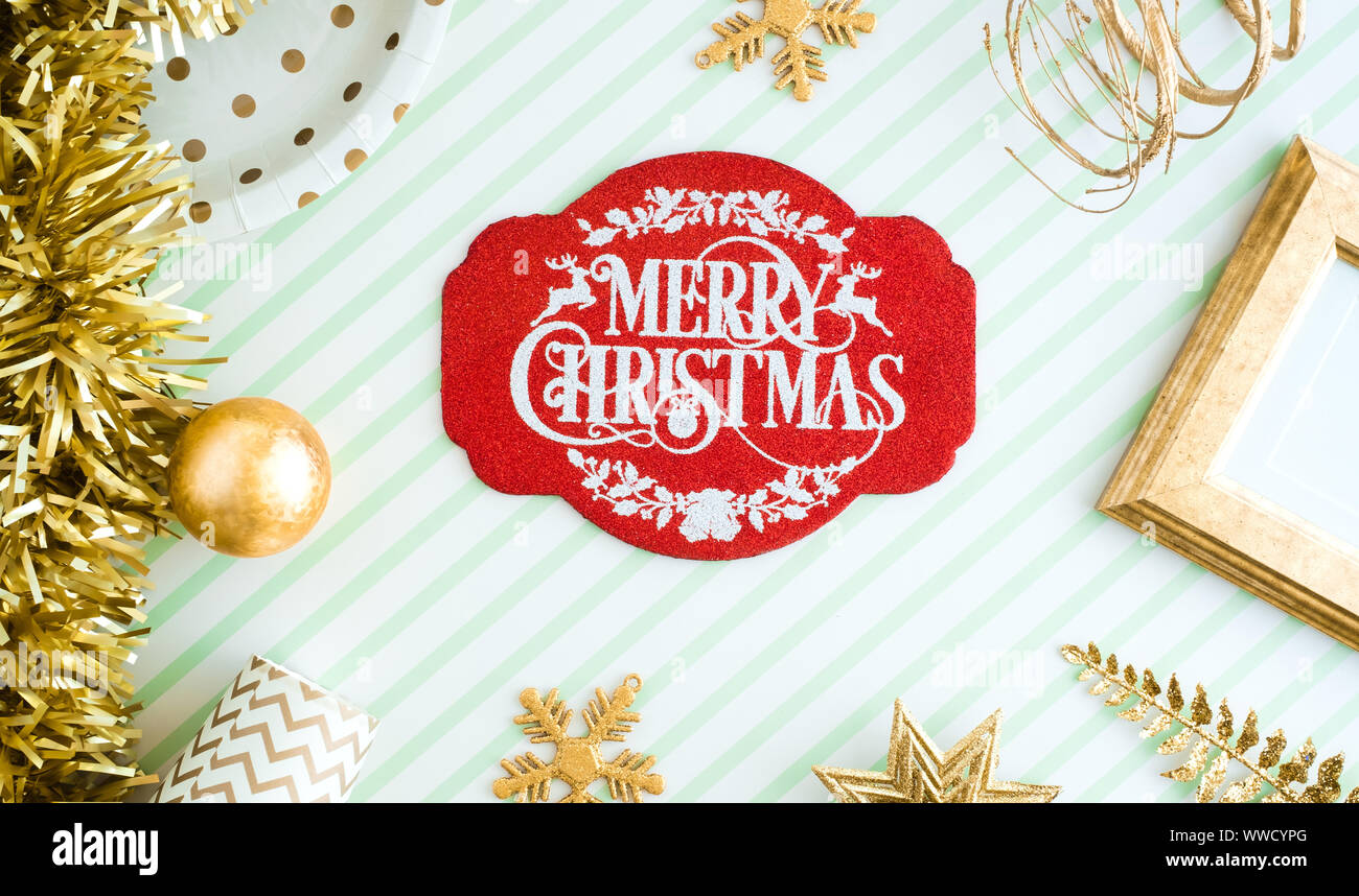 REd Merry christmas lable background.top view of sparkling gold tinsel,ball,ornament decorate on green strip line table.holiday celebration greeting c Stock Photo