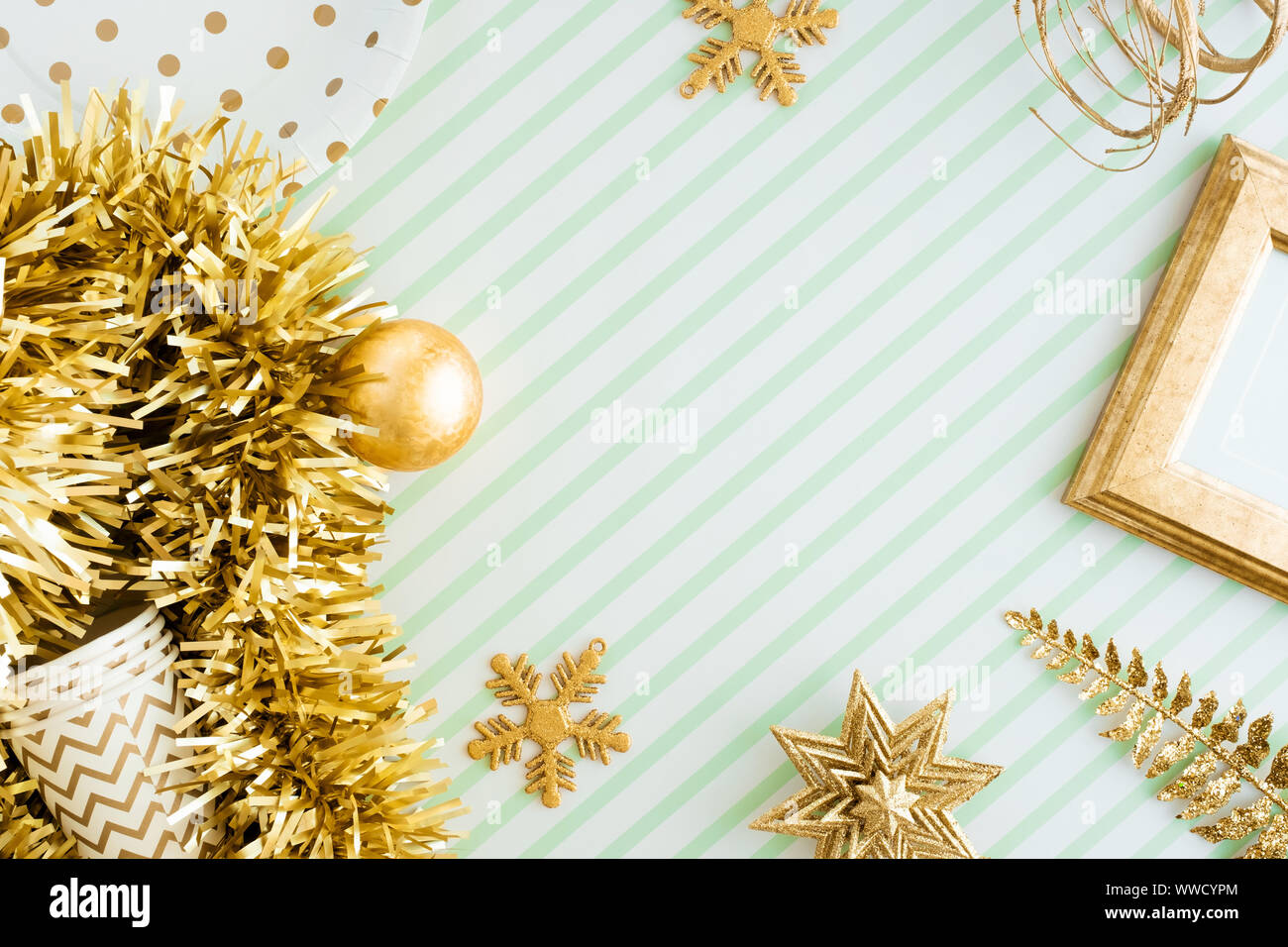 Merry christmas and happy new year background.top view of sparkling gold tinsel,ball,ornament decorate on green strip line table.holiday celebration g Stock Photo