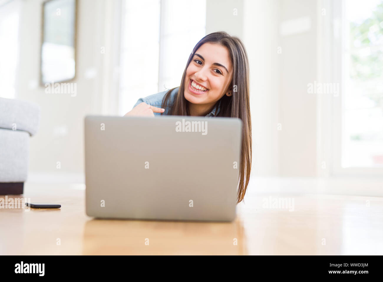 Beautiful young woman laying on the floor using laptop with surprise ...