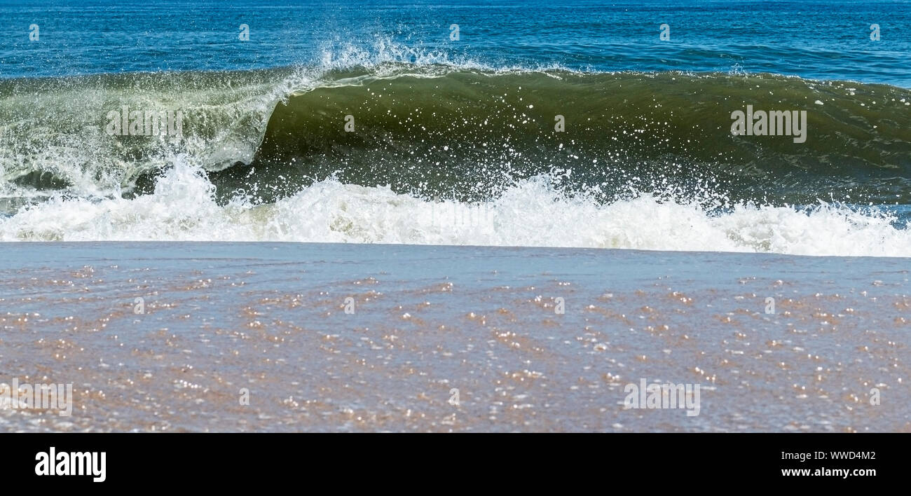 An Atlantic Ocean wave curling to the right is crashing on to the shore of Fire Island New York. Stock Photo