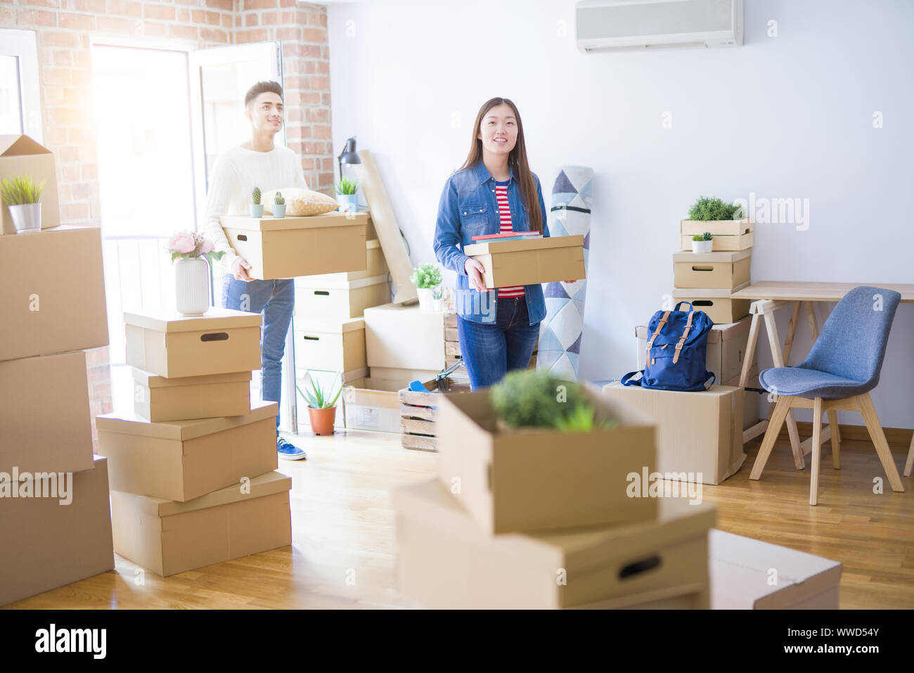 Beautiful young asian couple looking happy holding cardboard boxes ...
