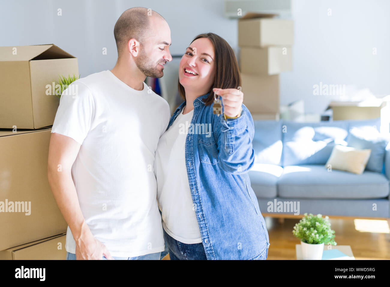 Young couple smiling very happy showing keys of new home, moving and ...