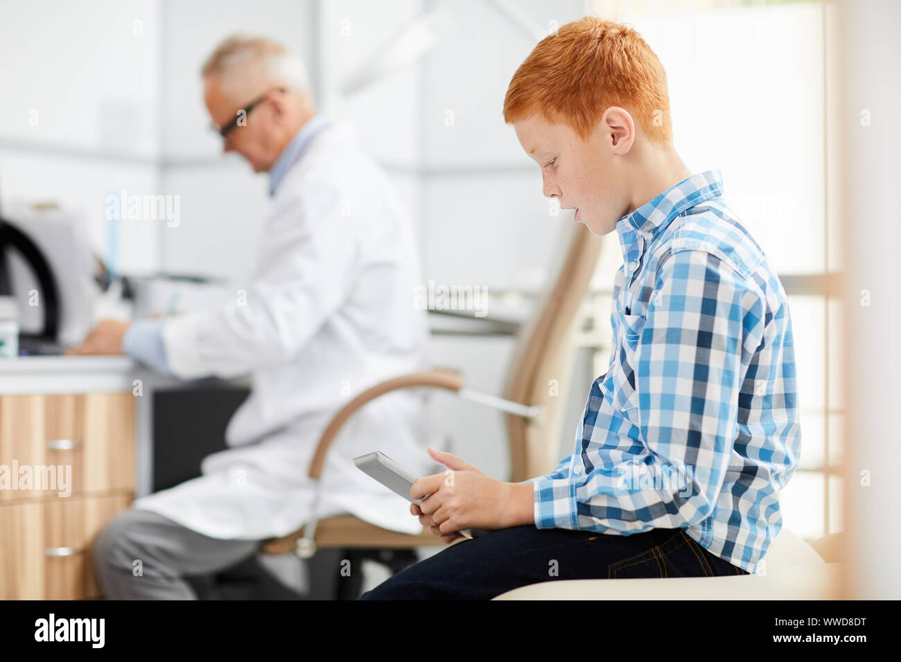 Side view portrait of red haired teenage boy using digital tablet in ...