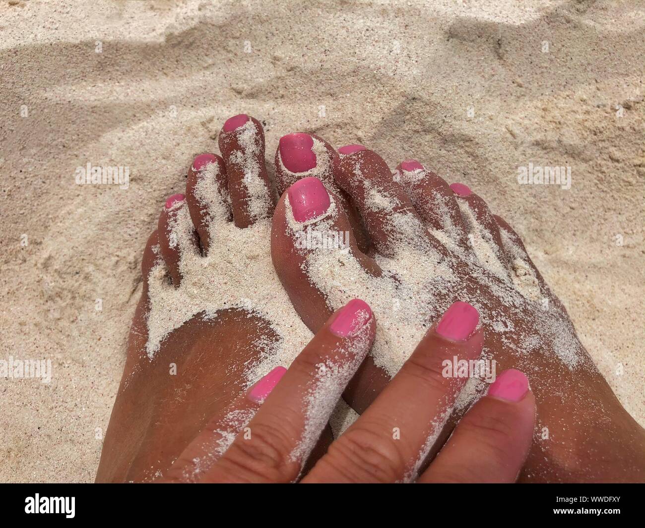 A woman's hand touching feet in the sand, Tulum, Yucatan Peninsula