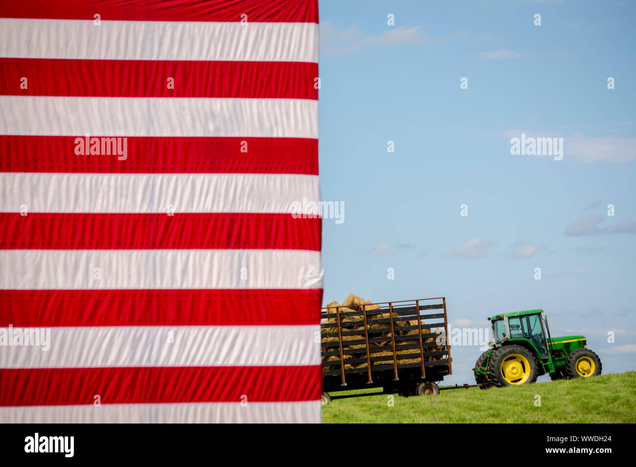 A John Deere tractor loaded with hay with the stars and stripes of the US Flag in the foreground set the stage for the annual barbeque hosted by Iowa Senator Tom Harkins. Stock Photo