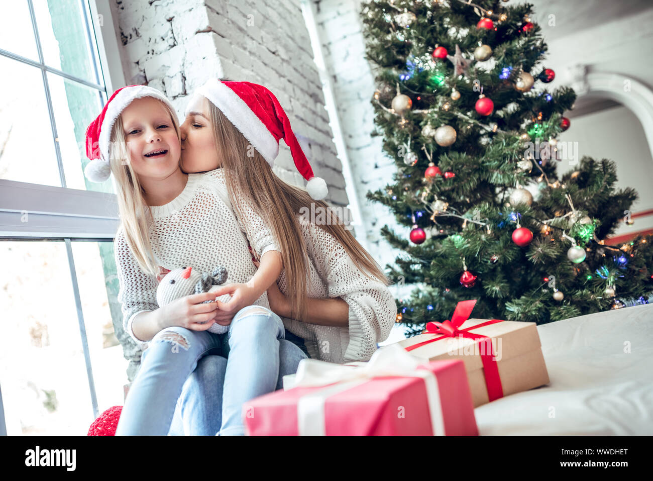 Mom and daughter dressed as Santa celebrate Christmas. Family at the Christmas tree. Woman and girl celebrate new year Stock Photo