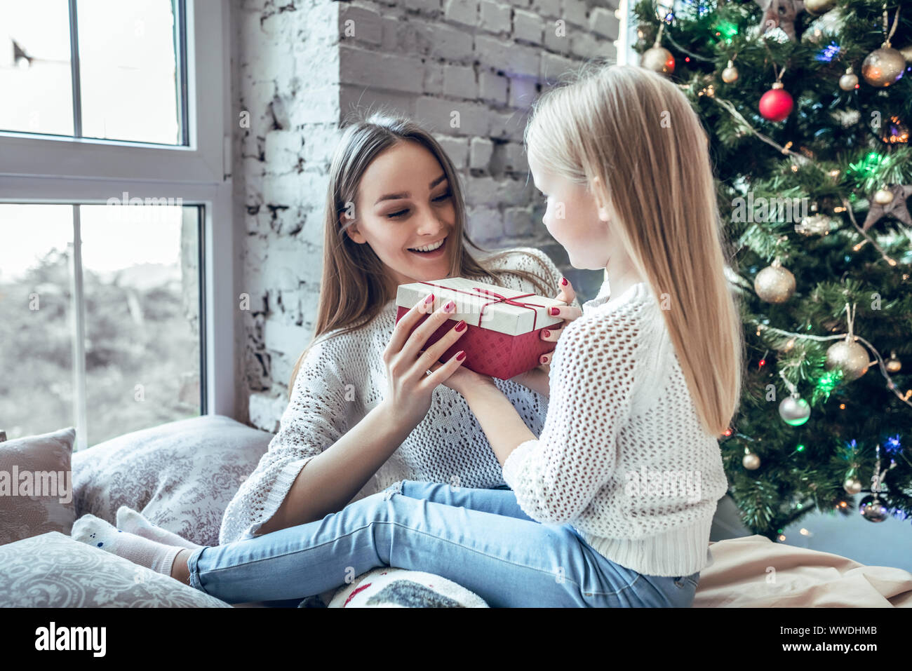 Happy family mother and child daughter on Christmas morning at the Christmas tree with gifts. Stock Photo