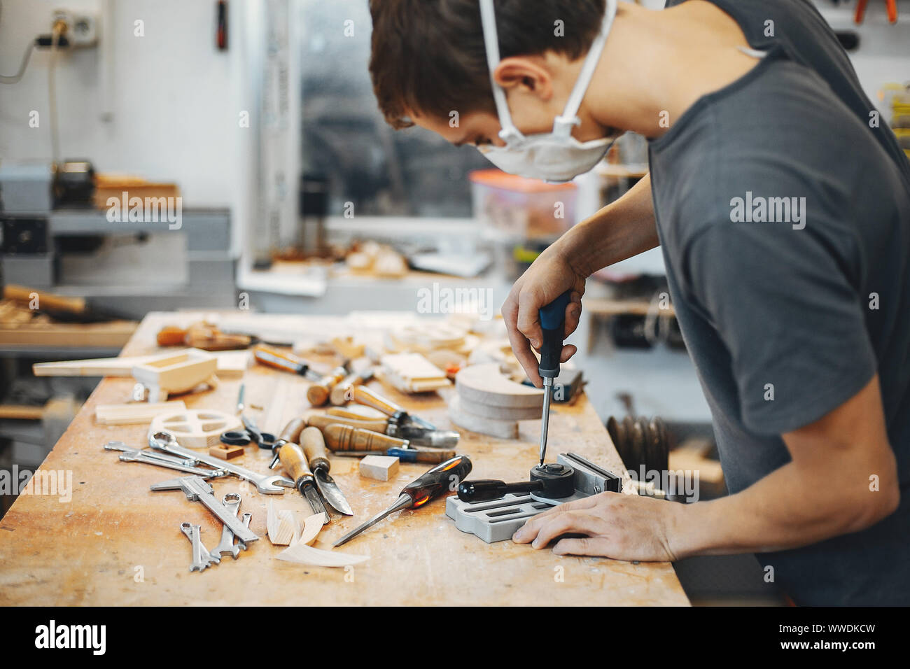 A man carves a tree. The carpenter works with screwdriver in a studio ...