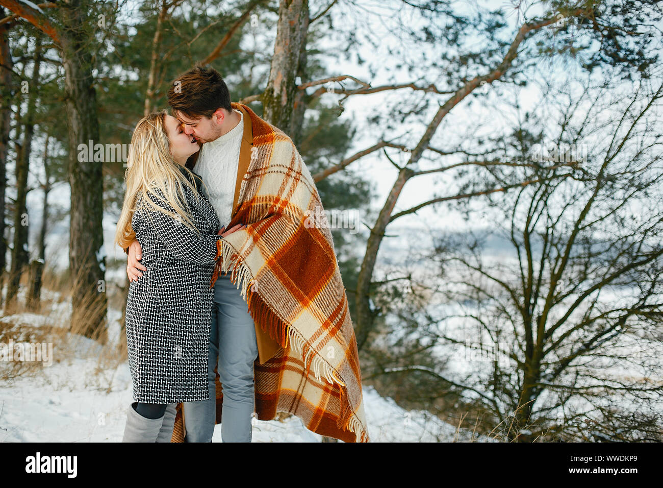 happy couple wrapped in a blanket standing in the park on a snowy day Stock Photo Alamy