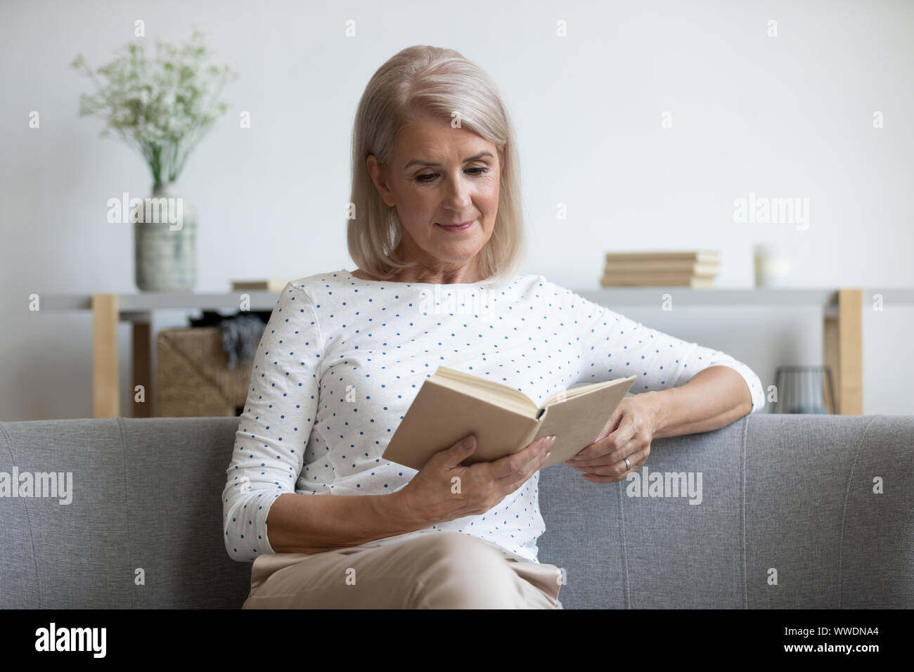 Mature woman couch reading book hi-res stock photography and images - Alamy