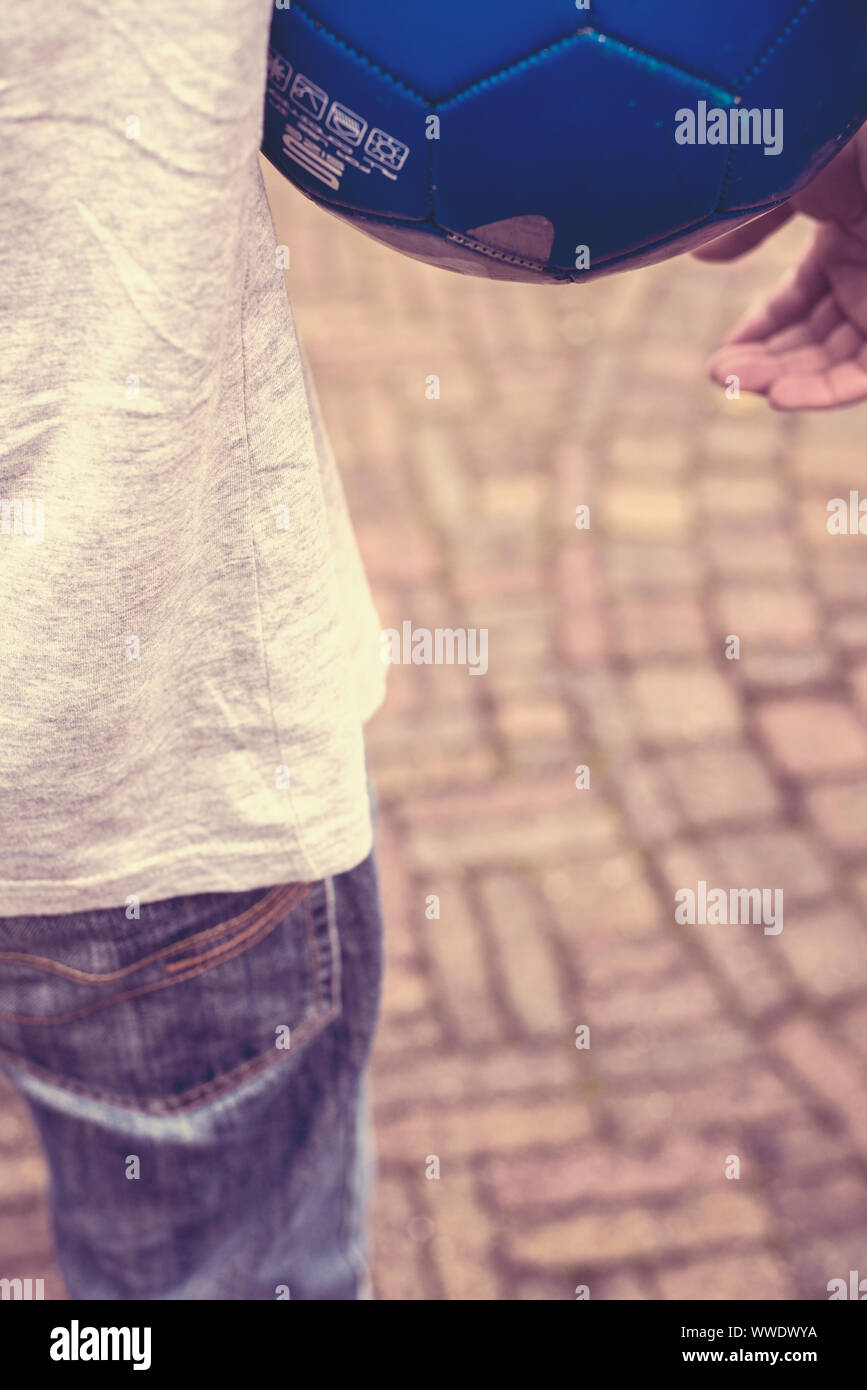 Detail of a teenage boy holding a blue football under his arm Stock Photo