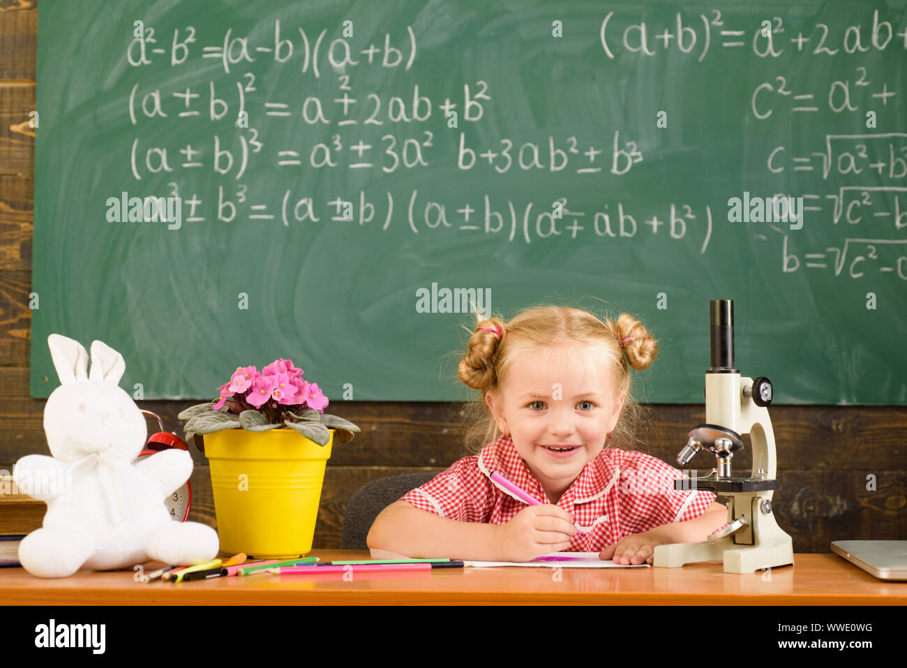 Schoolgirl do homework assignment on chalkboard background. Little ...