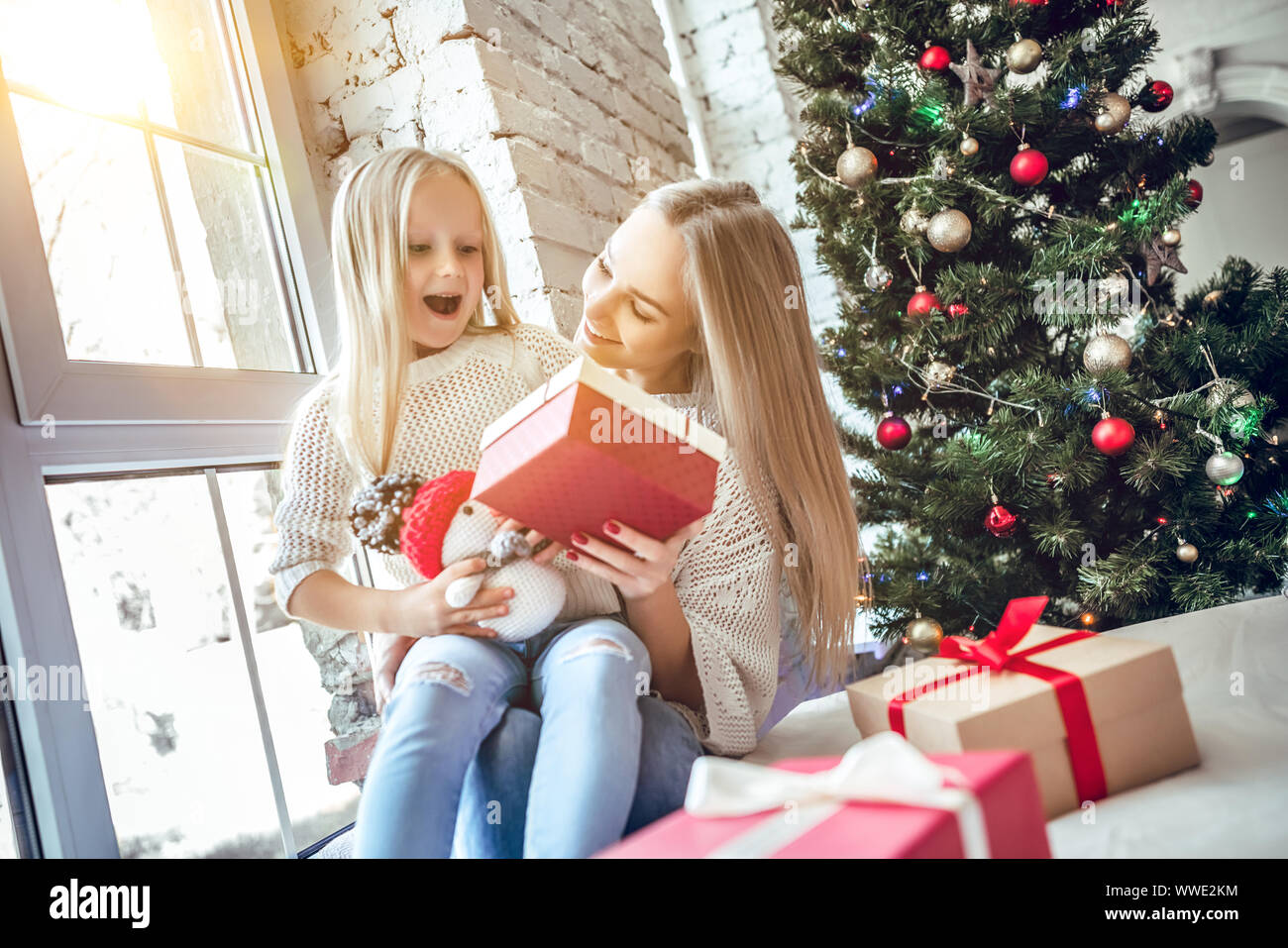Cheerful happy woman with daughter sitting on the floor in the living ...