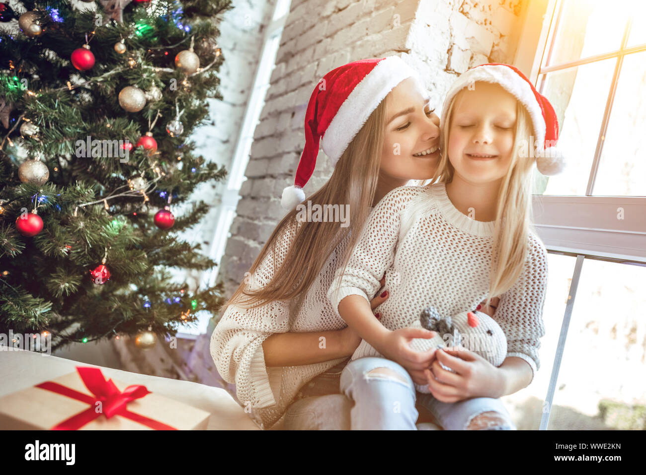 Happy family mother and child girl in santa hat near a Christmas tree ...