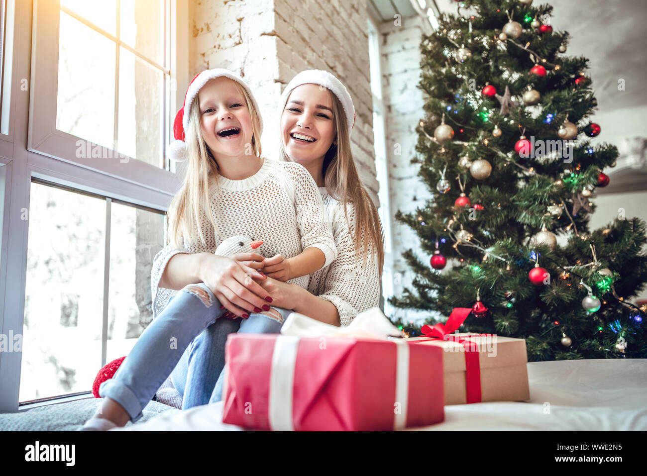 Christmas concept. Little girl with mother in red Santa hat near ...