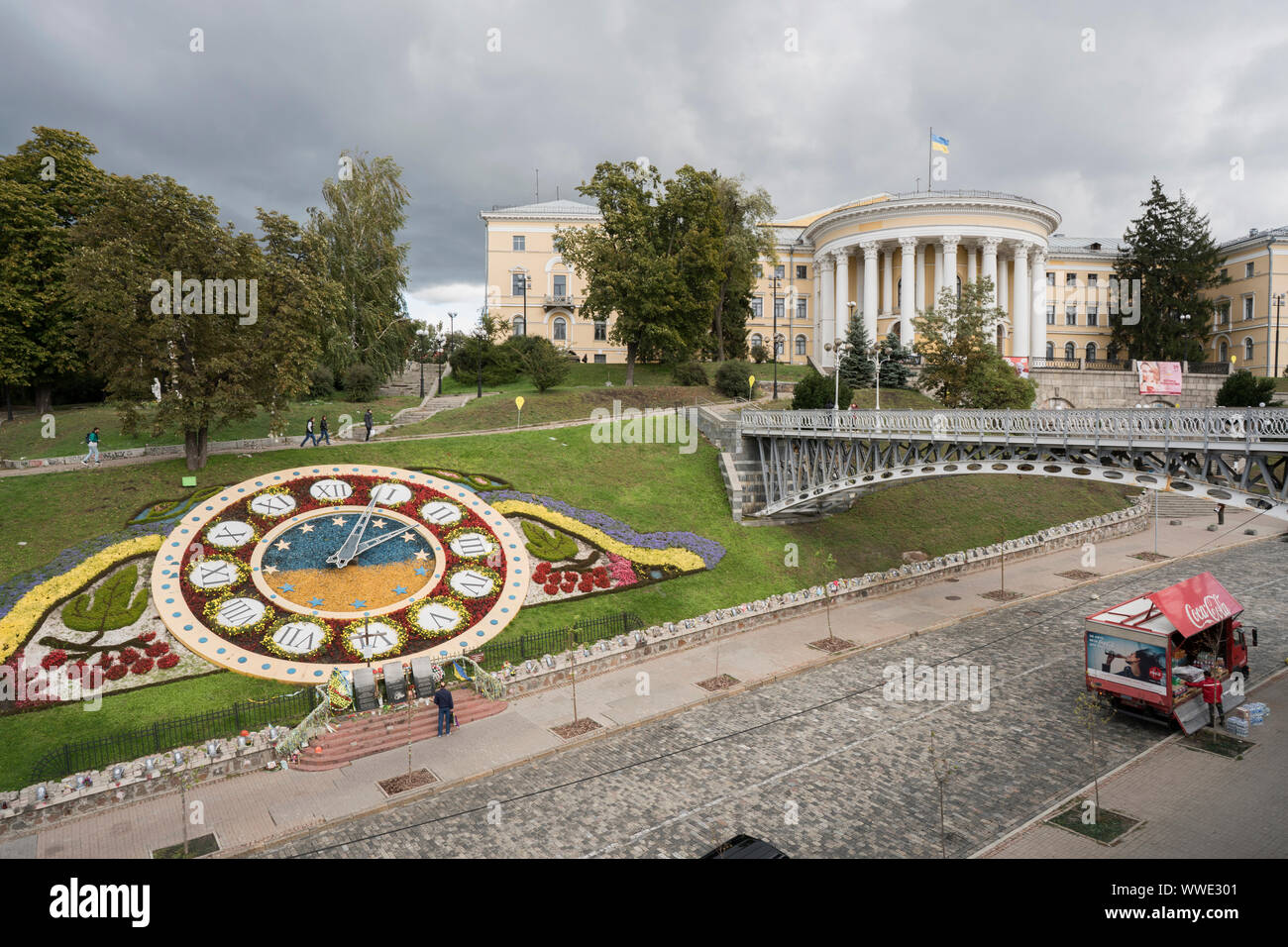 Flower Clock and Euromaidan Memorials on Heroyiv Nebesnoyi Sotni Alley with the performing art center, the October Palace of the Trade Union Federation of Ukraine, also known as International Centre of Culture and Arts in the Instytutska street close to Independence Square in the background. Pecherskyi District, city center, Kiev, Ukraine, Europe Stock Photo