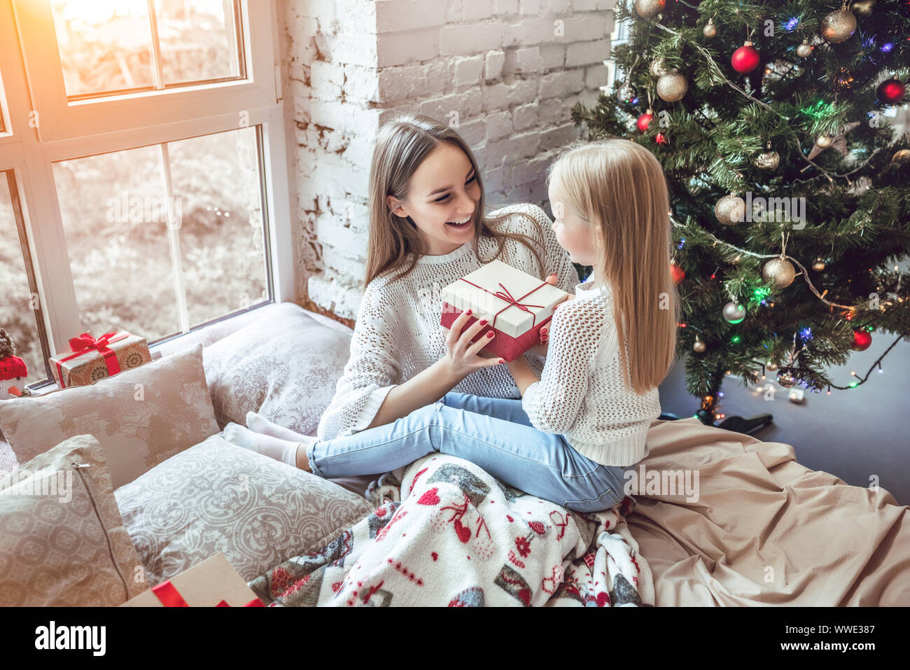 cute Asian daughter girl give her a mother hug after exchanging gifts.  Parent and little child having fun near tree indoors. Merry Christmas and  Happy Stock Photo - Alamy