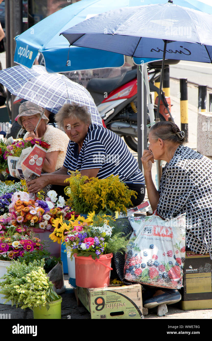 Belgrade, Serbia -  July 30, 2019: Three elderly women sitting under the sunshades and selling flowers in the street in the summer Stock Photo