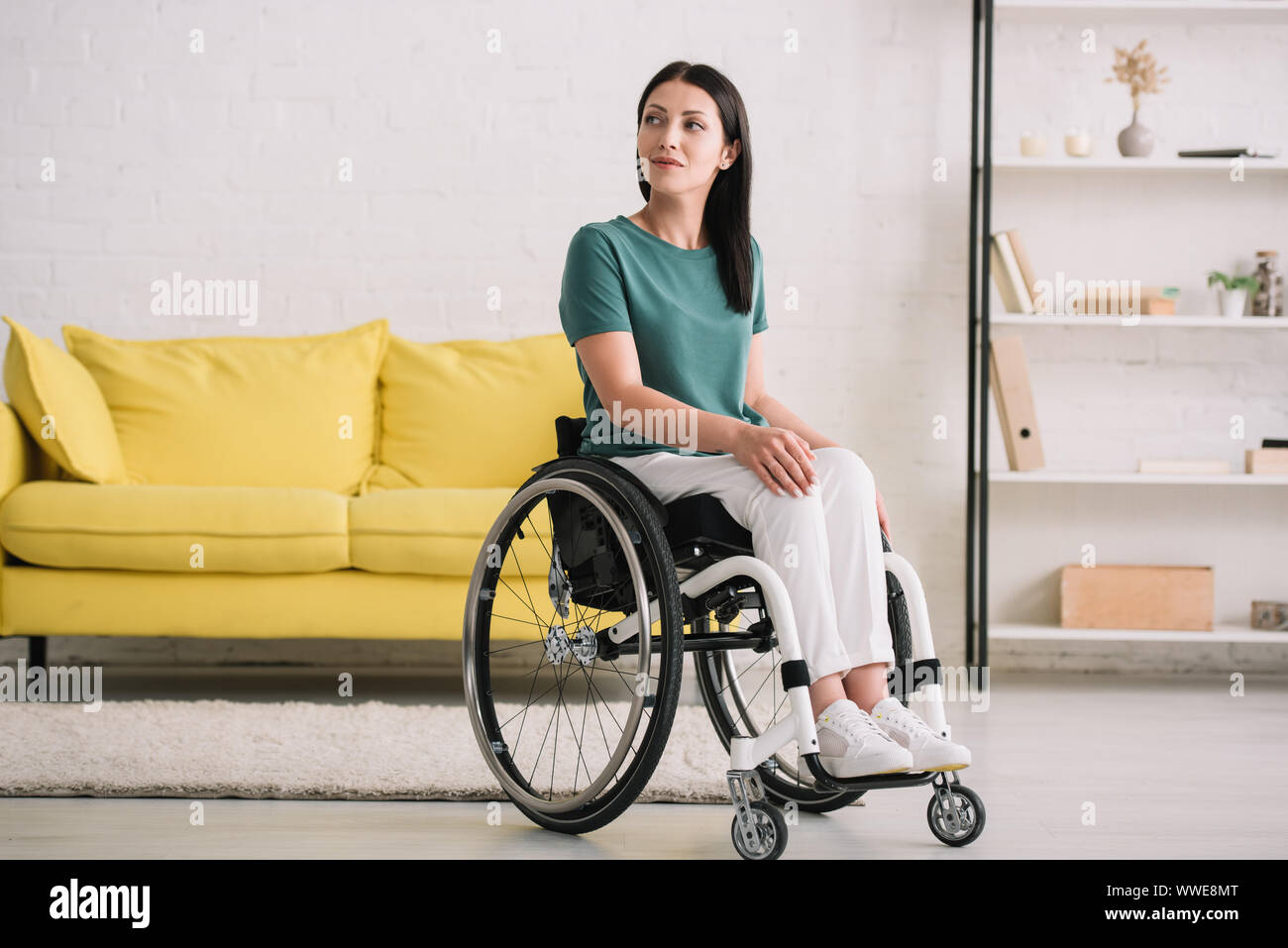 positive, smiling disabled woman looking away while sitting in ...