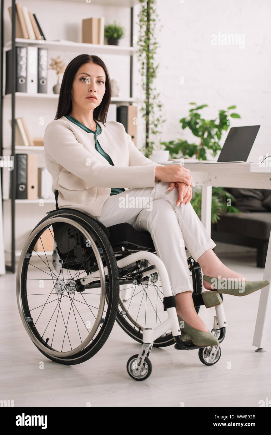 confident disabled businesswoman looking at camera while sitting in ...