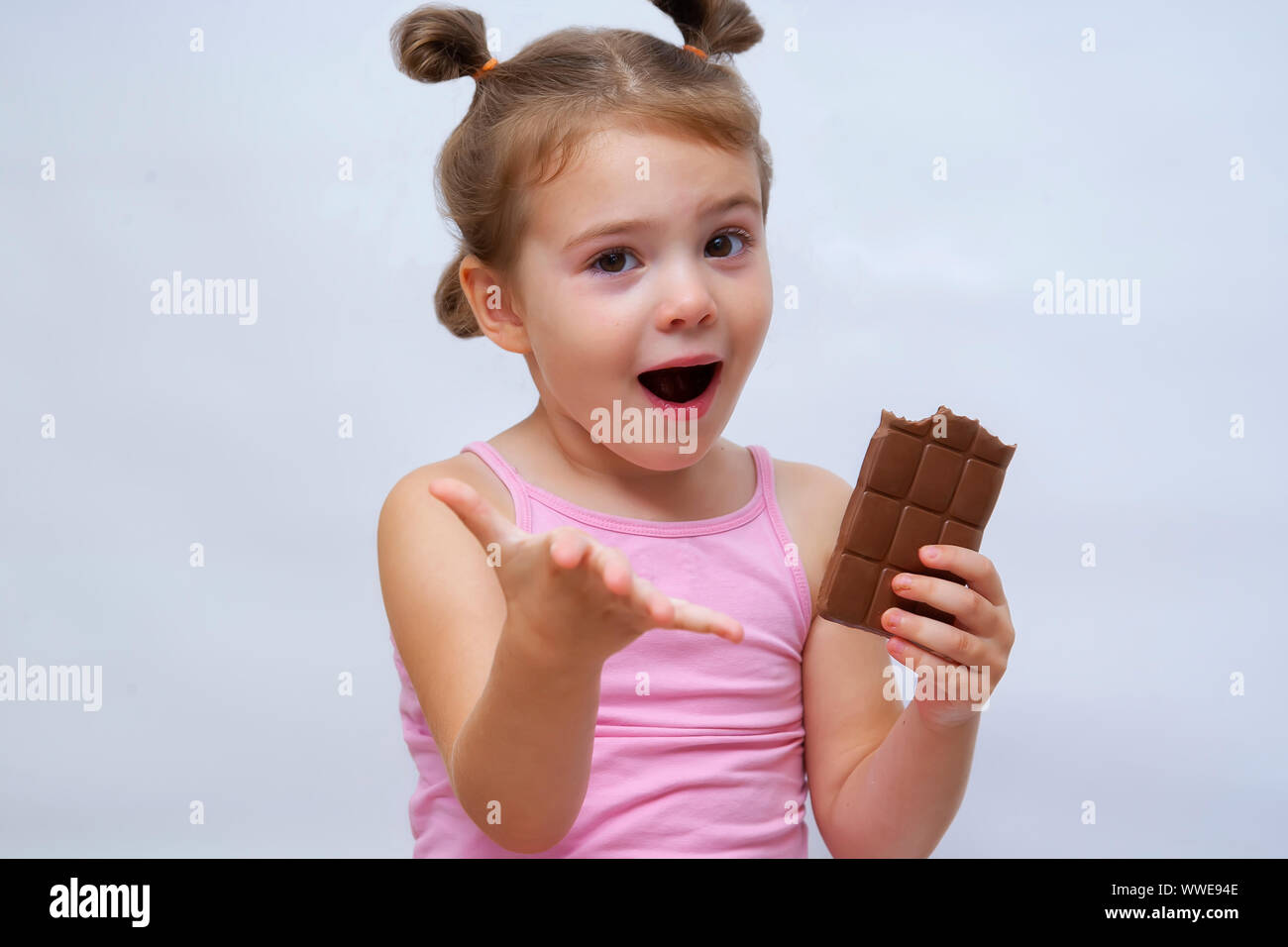 Surprised funny girl with open mouth holding chocolate and looking