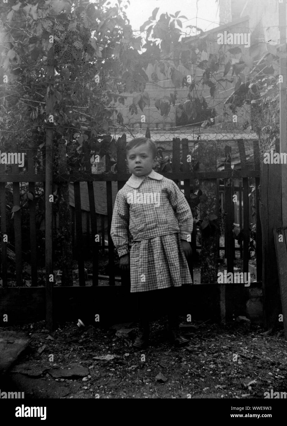 AJAXNETPHOTO. 1889-1900 (APPROX). FRANCE (EXACT LOCATION UNKNOWN.). - FAMILY SNAPSHOT - YOUNG PERSON IN CHEQUERED OUTFIT IN FENCED GARDEN ENVIRONMENT. IMAGE FROM ORIGINAL GLASS PLATE NEGATIVE; DATE SOURCE FROM GLASS PLATE BOX LID.  PHOTOGRAPHER:UNKNOWN © DIGITAL IMAGE COPYRIGHT AJAX VINTAGE PICTURE LIBRARY SOURCE: AJAX VINTAGE PICTURE LIBRARY COLLECTION REF:AVL PEO FRA 1889 103 Stock Photo