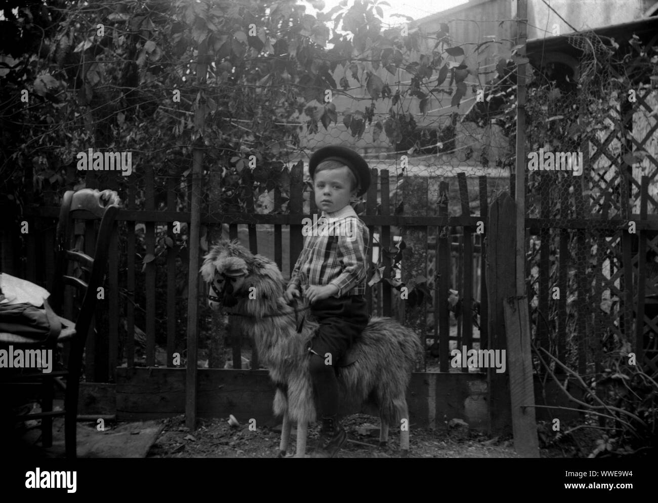 AJAXNETPHOTO. 1889-1900 (APPROX). FRANCE (EXACT LOCATION UNKNOWN.). - FAMILY SNAPSHOT - YOUNG BOY IN CHECK SHIRT, BREACHES AND BERET ASTRIDE A WOODEN FURRY TOY HORSE IN FENCED GARDEN ENVIRONMENT. IMAGE FROM ORIGINAL GLASS PLATE NEGATIVE; DATE SOURCE FROM GLASS PLATE BOX LID.  PHOTOGRAPHER:UNKNOWN © DIGITAL IMAGE COPYRIGHT AJAX VINTAGE PICTURE LIBRARY SOURCE: AJAX VINTAGE PICTURE LIBRARY COLLECTION REF:AVL PEO FRA 1889 104 Stock Photo