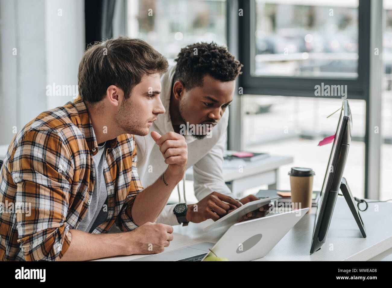 african american programmer using digital tablet while working with colleague in office Stock Photo