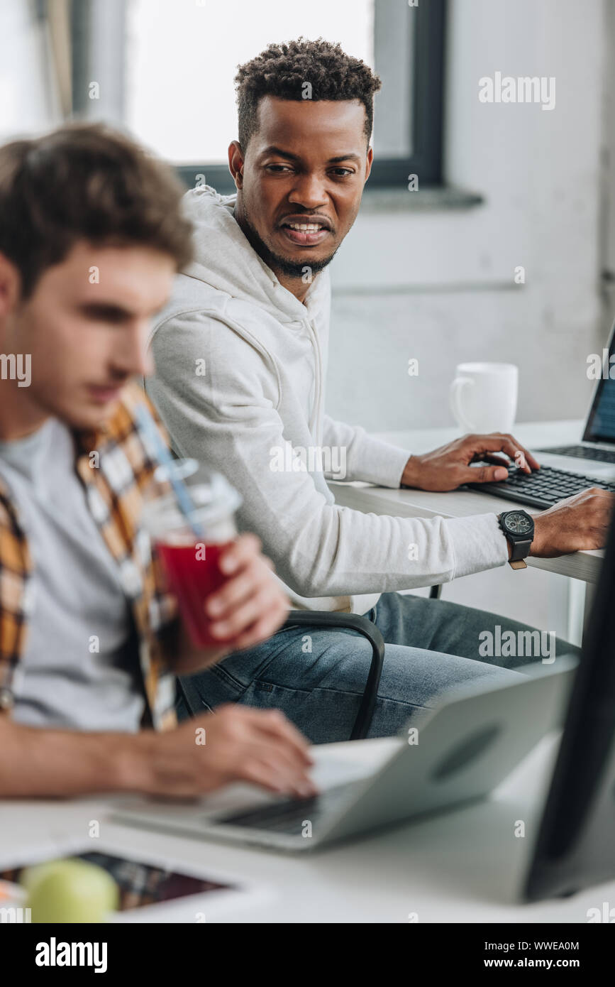 selective focus of angry african american programmer looking at ...