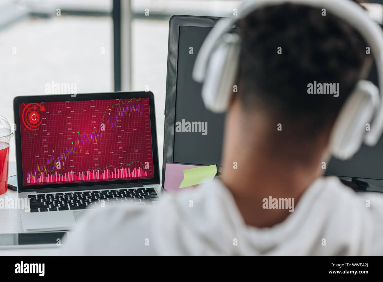 back view of african american programmer in headphones looking at ...