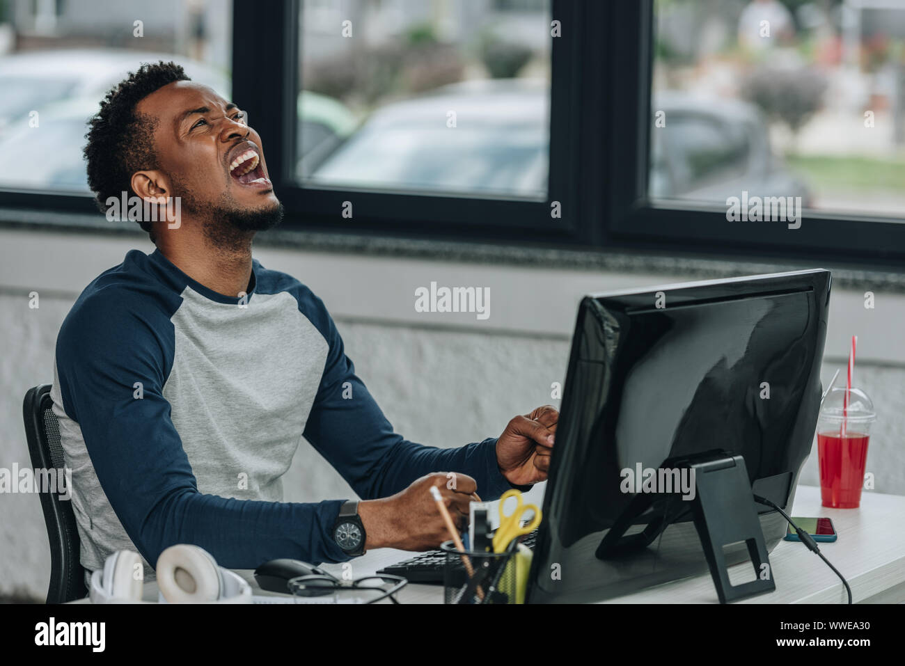 angry african american programmer gesturing while sitting at workplace ...